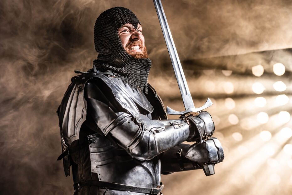 handsome knight in armor holding sword and fighting on black background