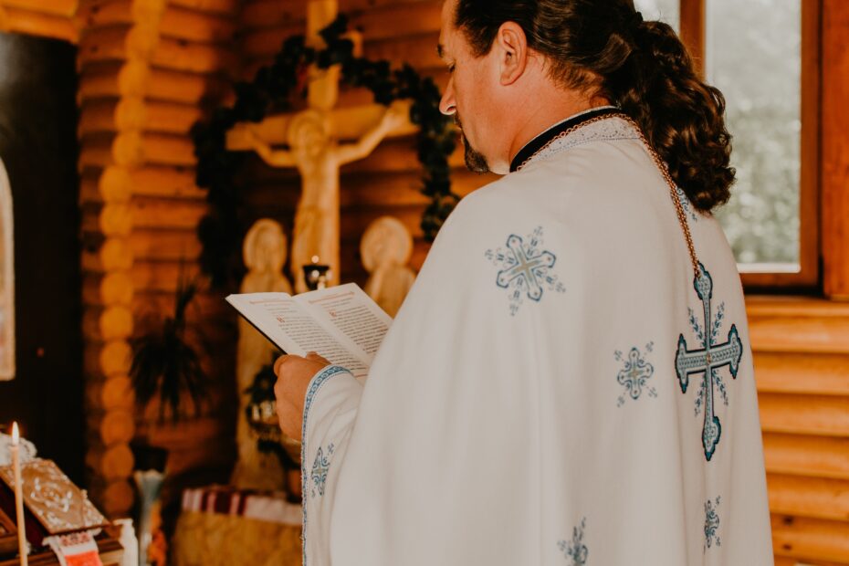 priest in cassock holds holy book of Bible and reads