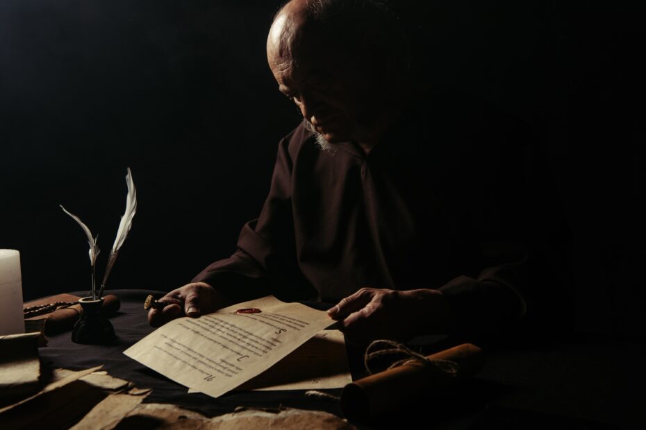 senior monk looking at manuscript with wax seal isolated on black