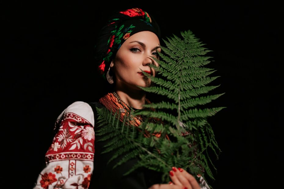 Witch woman collects herbs, ferns at night in Carpathian mountains forest.